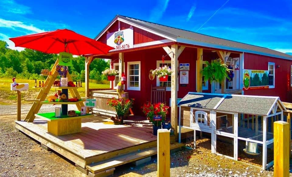 The shop front of Roosters Market. The building resembles a red shed. There is produce for sale out front.